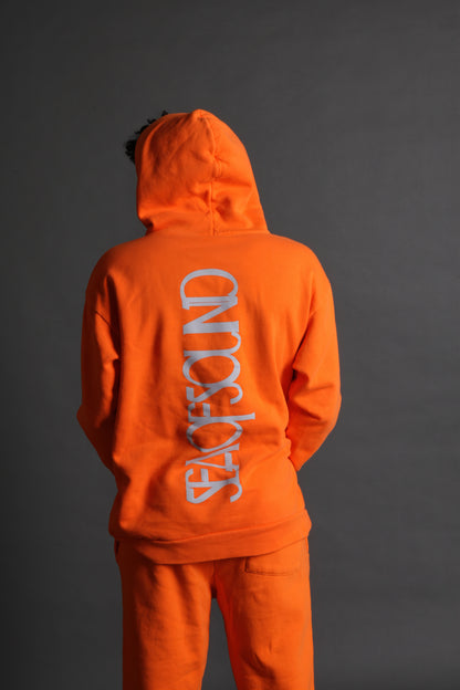 The model is wearing the orange and grey Righteous Hoodie from Sea Of Sound by Gavin Rossdale with the main Sea Of Sound logo on the back