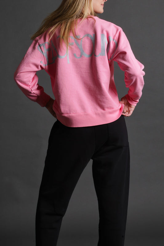The model is wearing the pink and white crewneck from Sea Of Sound by Gavin Rossdale with the main Sea Of Sound logo on the back