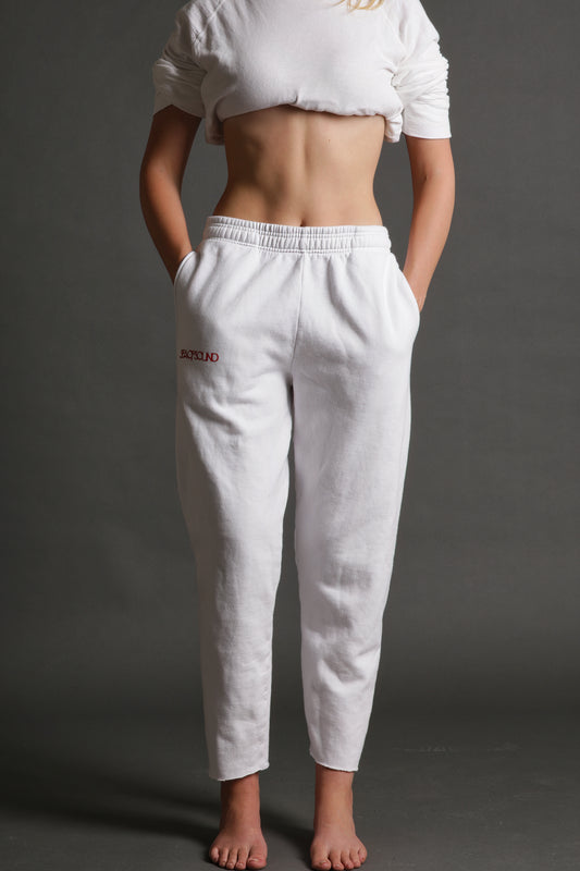 The model is wearing the white and red track pant from Sea Of Sound by Gavin Rossdale with the main Sea Of Sound logo on the top part of the right leg.
