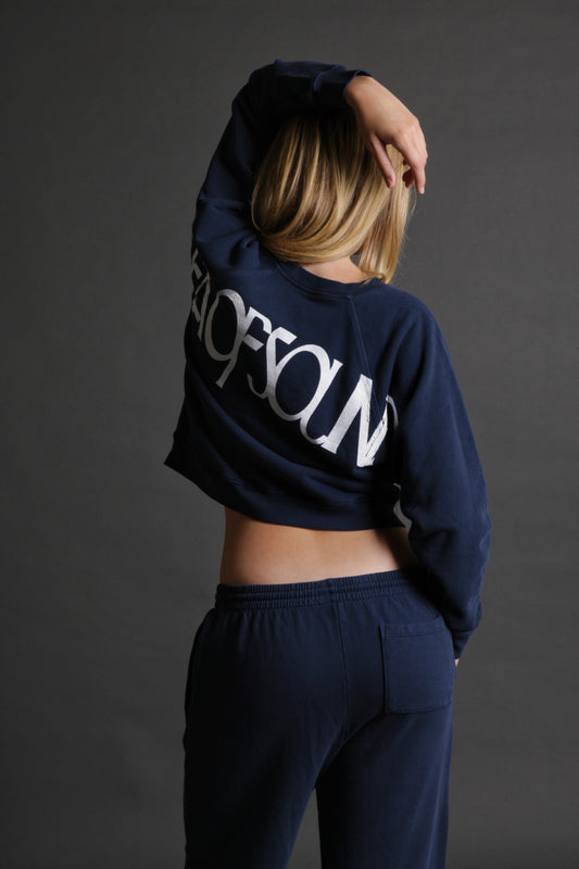 The model is wearing a navy crewneck from Sea Of Sound by Gavin Rossdale with the main Sea Of Sound logo on the back
