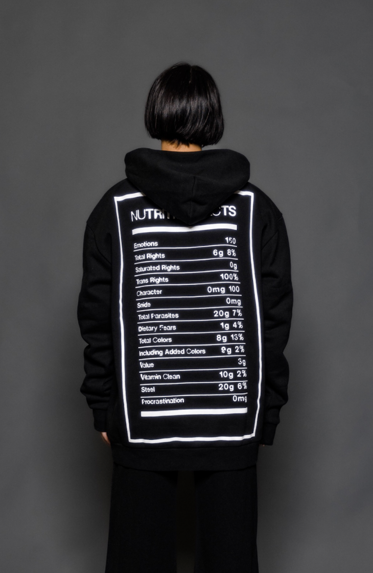 The model is wearing the black and white premium hoodie from Sea Of Sound by Gavin Rossdale with the Nutrition Facts logo on the back.