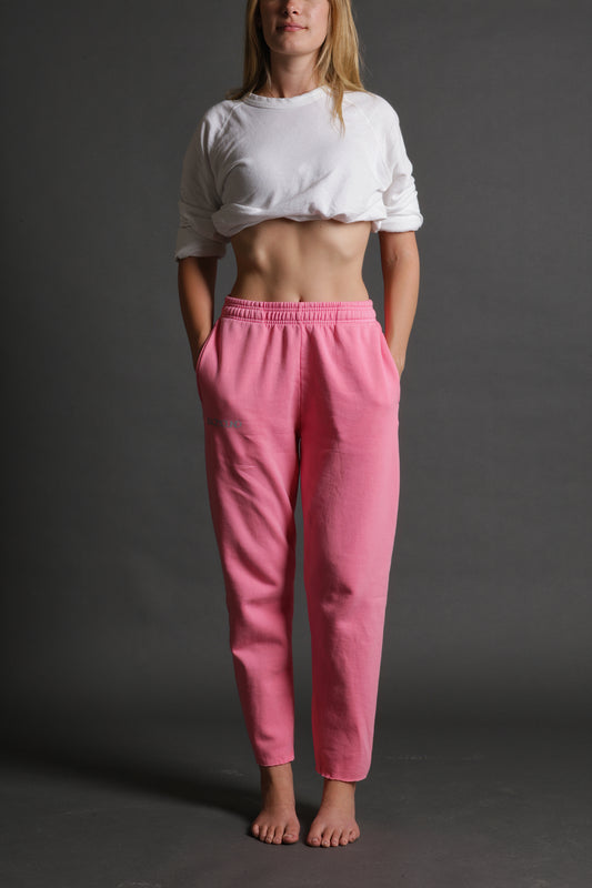 The model is wearing the pink and grey track pant from Sea Of Sound by Gavin Rossdale with the main Sea Of Sound logo on the top part of the right leg.