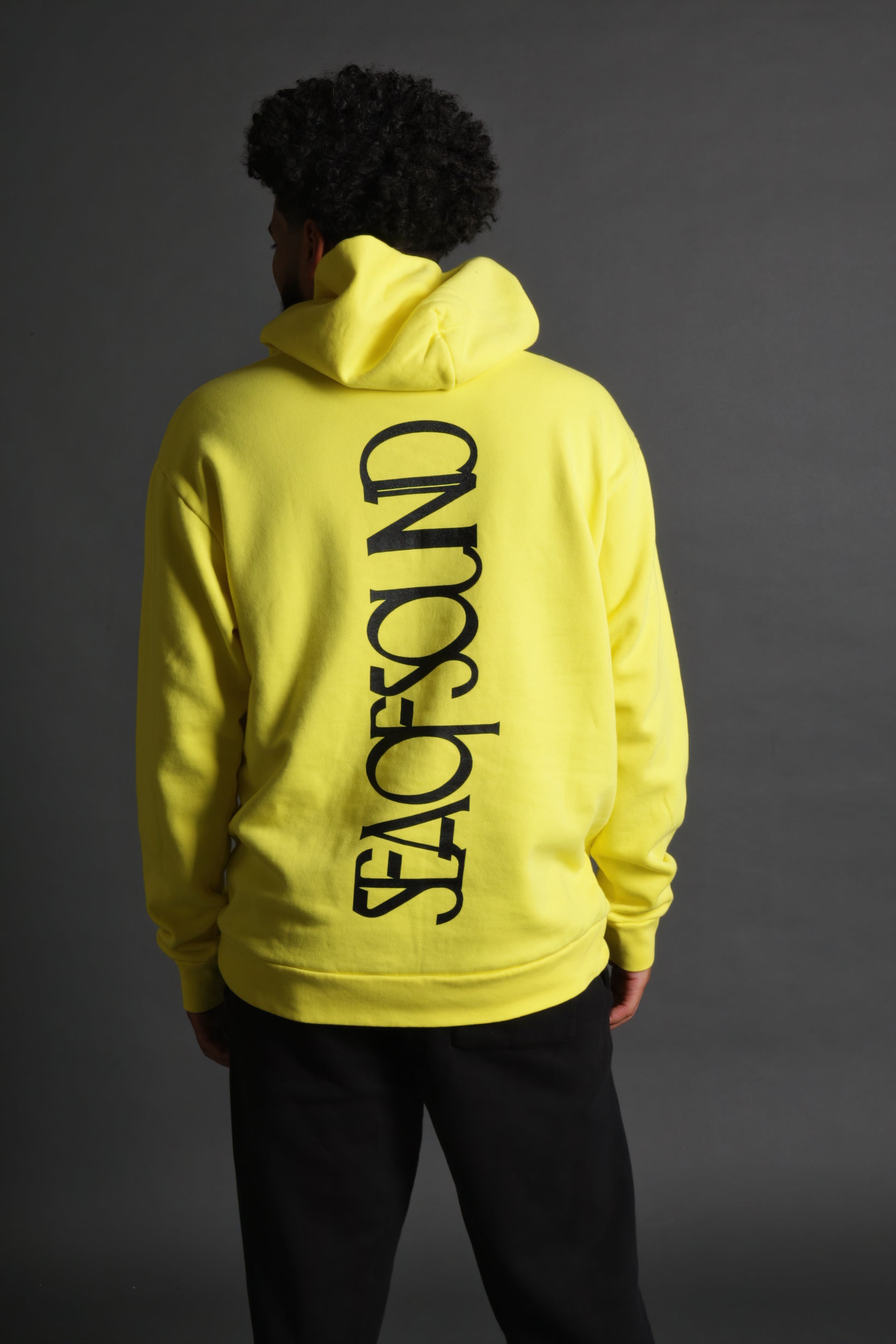 The model is wearing the yellow and black Righteous Hoodie from Sea Of Sound by Gavin Rossdale with the main Sea Of Sound logo vertical on the back.