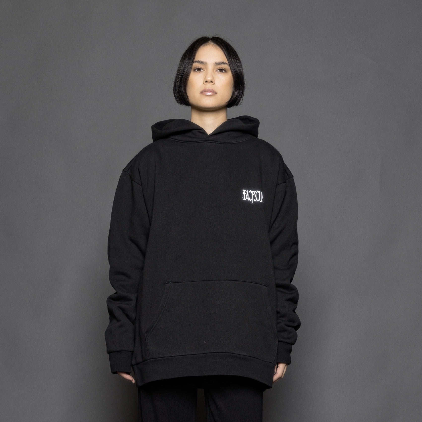 The model is wearing the black and white premium hoodie from Sea Of Sound by Gavin Rossdale with the main Sea Of Sound logo on the front.